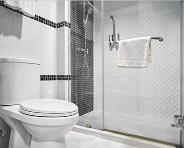 Compact bathroom with a glass shower, black and white tile accents, and a white toilet.