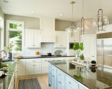 Bright kitchen with white cabinets, black countertops, and glass pendant lights.