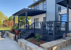 Backyard patio with a black pergola, raised deck, and stone retaining walls