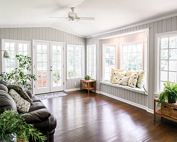 Bright living room with large windows, a window seat, and indoor plants