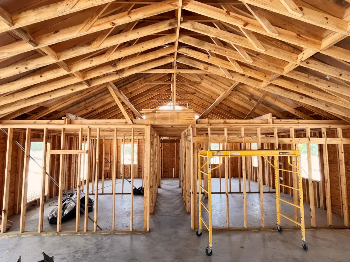 Wooden house interior under construction with exposed beams and framed walls.